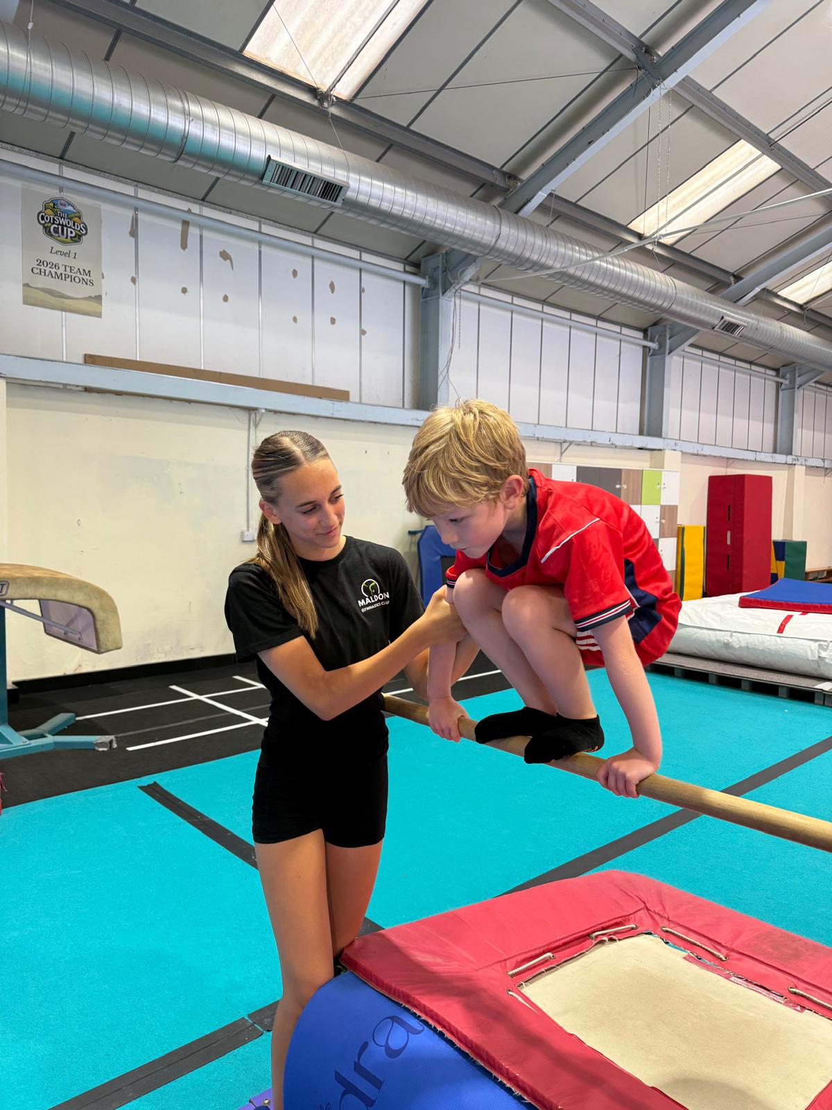 Coach supporting a young gymnast on the bar at Maldon Gymnastics Club