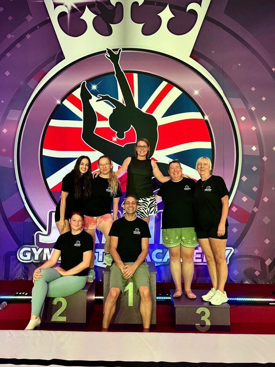 The Maldon Gymnastics Club coaching team celebrating together on a competition podium